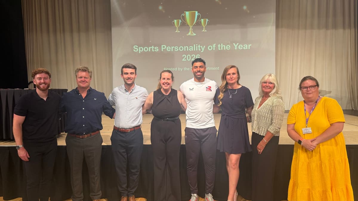 Teachers and guests stand together on stage at a school sports awards evening.